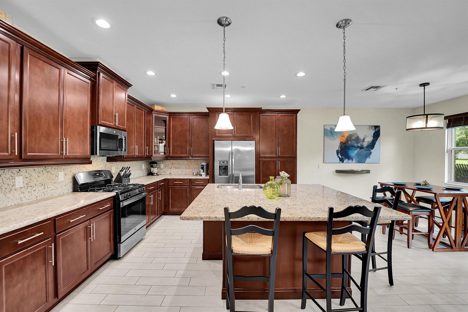 A kitchen features dark wood cabinets, granite countertops, a central island, and a dining area — 3162 NW 124th Way, Sunrise FL 33323, SUNRISE, FL