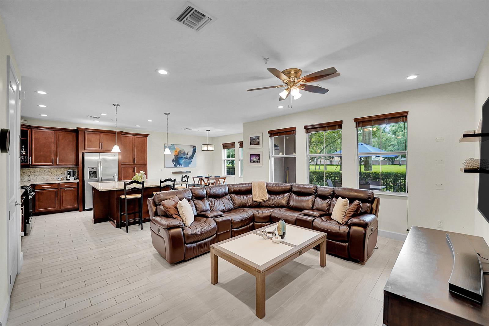 An open-concept living room and kitchen featuring a large brown leather sectional and tile flooring — 3162 NW 124th Way, Sunrise FL 33323, SUNRISE, FL