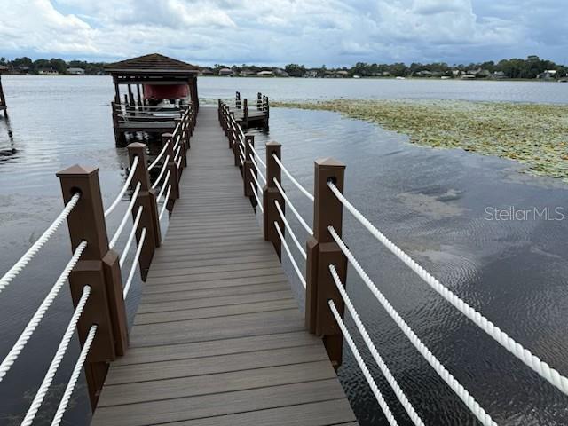 A wooden dock with rope railings extends over a lake toward a boat house — 9245 SOUTHERN BREEZE DRIVE, ORLANDO, FL