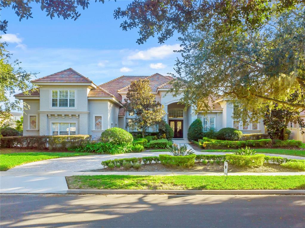 A two-story house with a tiled roof, light-colored stucco exterior, and a circular driveway — 9245 SOUTHERN BREEZE DRIVE, ORLANDO, FL