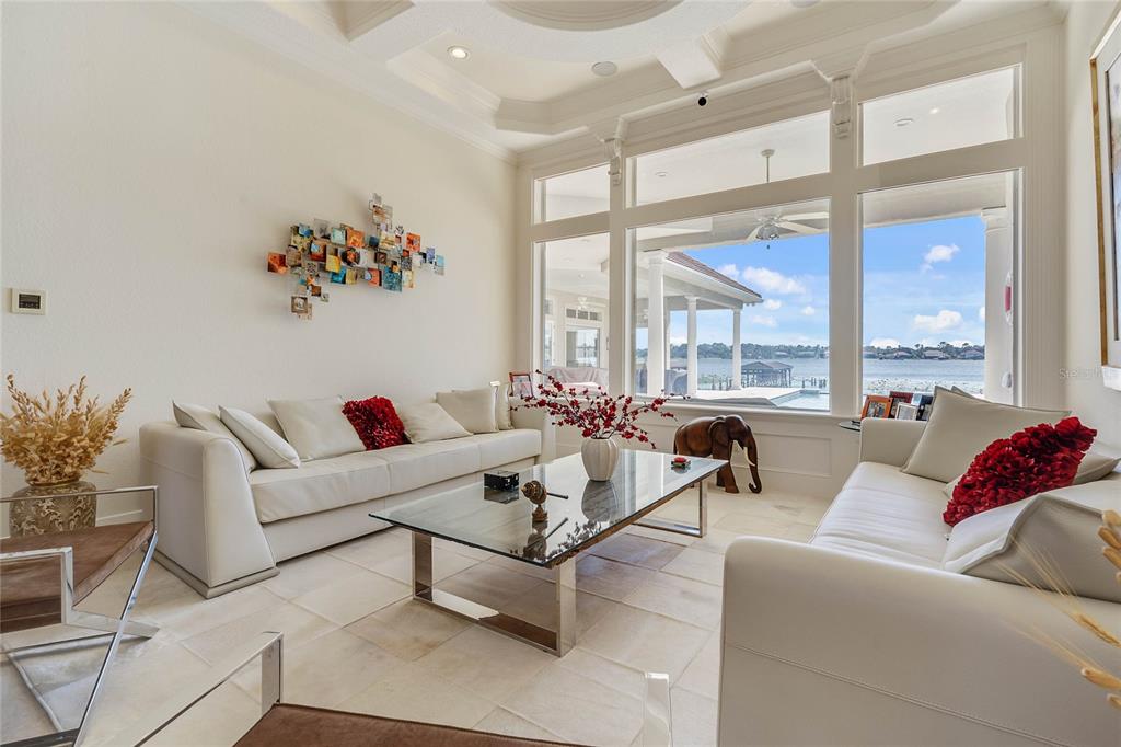 A bright living room features white sofas, a glass coffee table, and large waterfront windows — 9245 SOUTHERN BREEZE DRIVE, ORLANDO, FL