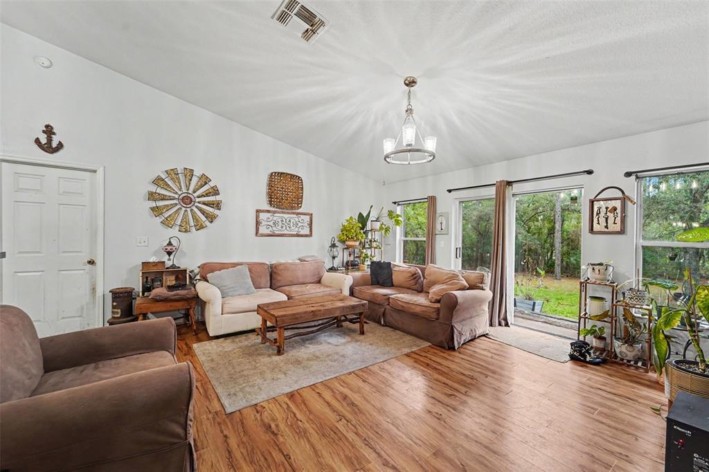 A living room features wood-look flooring, a chandelier, two sofas, and sliding glass patio doors — 1210 W FAN DRIVE, CITRUS SPRINGS, FL