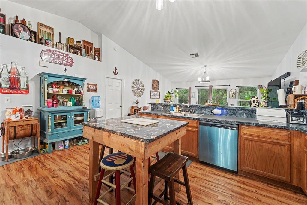 A kitchen features wood cabinets, a stone-topped island, and a blue hutch against white walls — 1210 W FAN DRIVE, CITRUS SPRINGS, FL