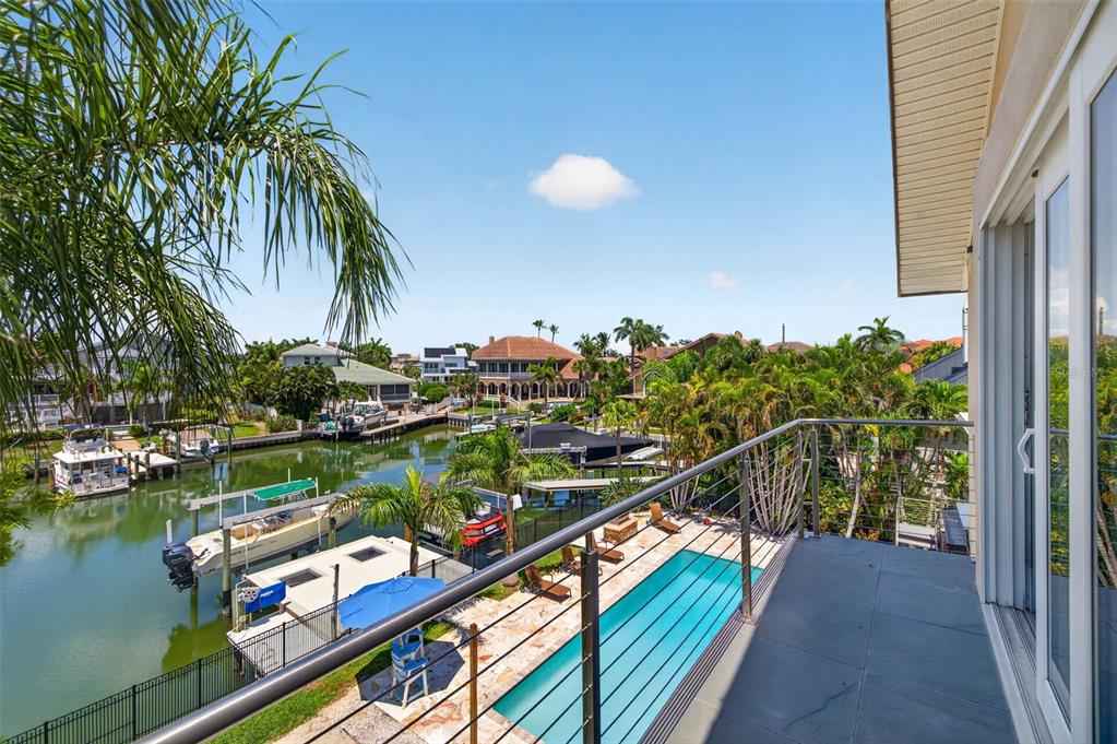 A balcony overlooks a swimming pool, a canal with docked boats, and surrounding tropical homes — 113 7TH STREET E, ST PETERSBURG, FL