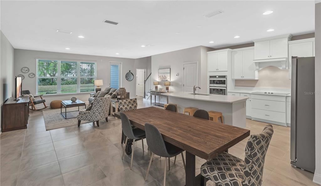 An open-concept kitchen, dining area, and living room featuring tile floors and white cabinetry — 7511 SEA OAK COURT, PARRISH, FL