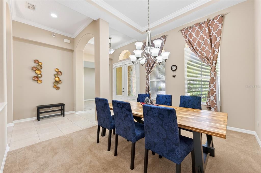 A dining room features a wooden table, blue patterned chairs, and a chandelier — 2425 PARKSIDE MEADOW DRIVE, APOPKA, FL