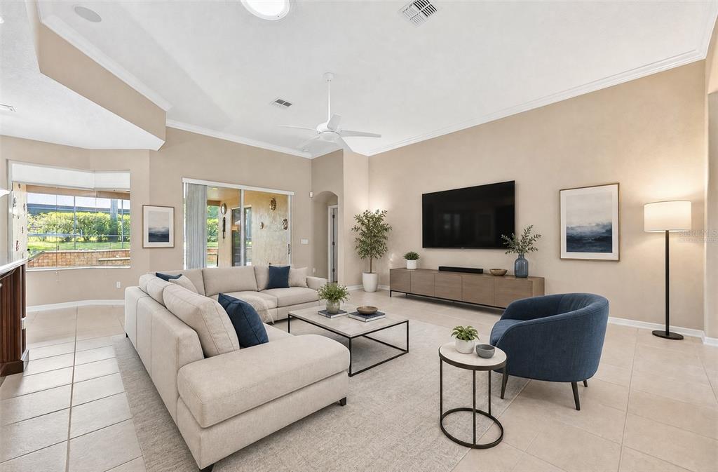 A spacious living room features a beige sectional sofa, blue armchair, and a large television — 2425 PARKSIDE MEADOW DRIVE, APOPKA, FL