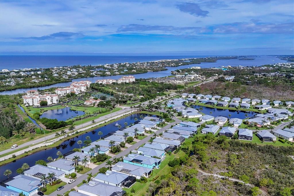 Aerial view of a coastal residential community featuring houses, ponds, and nearby ocean waters — 10446 COQUINA COURT, PLACIDA, FL