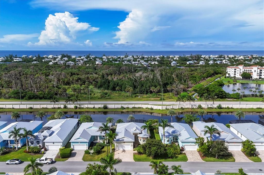 An aerial view shows a row of coastal houses with metal roofs facing a canal — 10446 COQUINA COURT, PLACIDA, FL