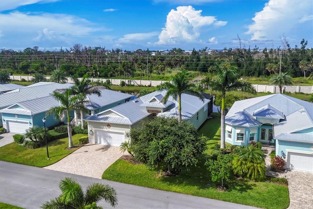 An aerial view shows three suburban houses with metal roofs and palm trees — 10446 COQUINA COURT, PLACIDA, FL