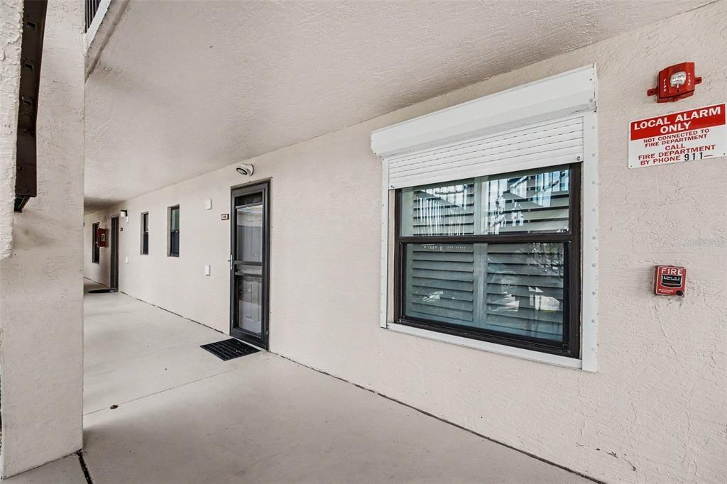 An exterior view of an apartment building walkway with a door, window, and alarm system — 4250 A1A S UNIT I-16, ST AUGUSTINE, FL