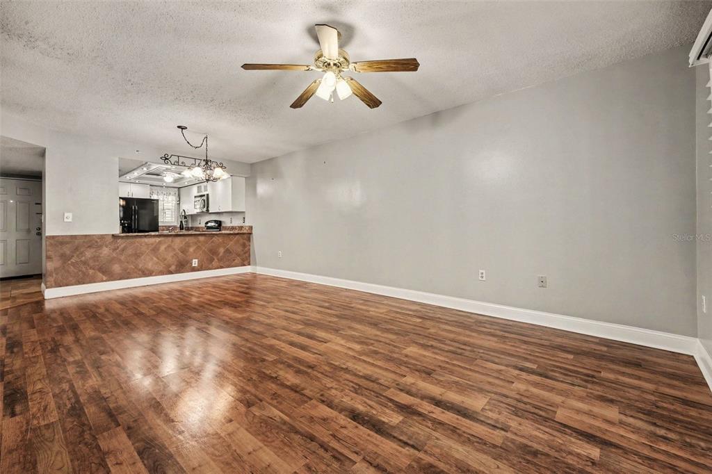 A living room with wood-look flooring, a ceiling fan, and a view into the kitchen — 4250 A1A S UNIT I-16, ST AUGUSTINE, FL