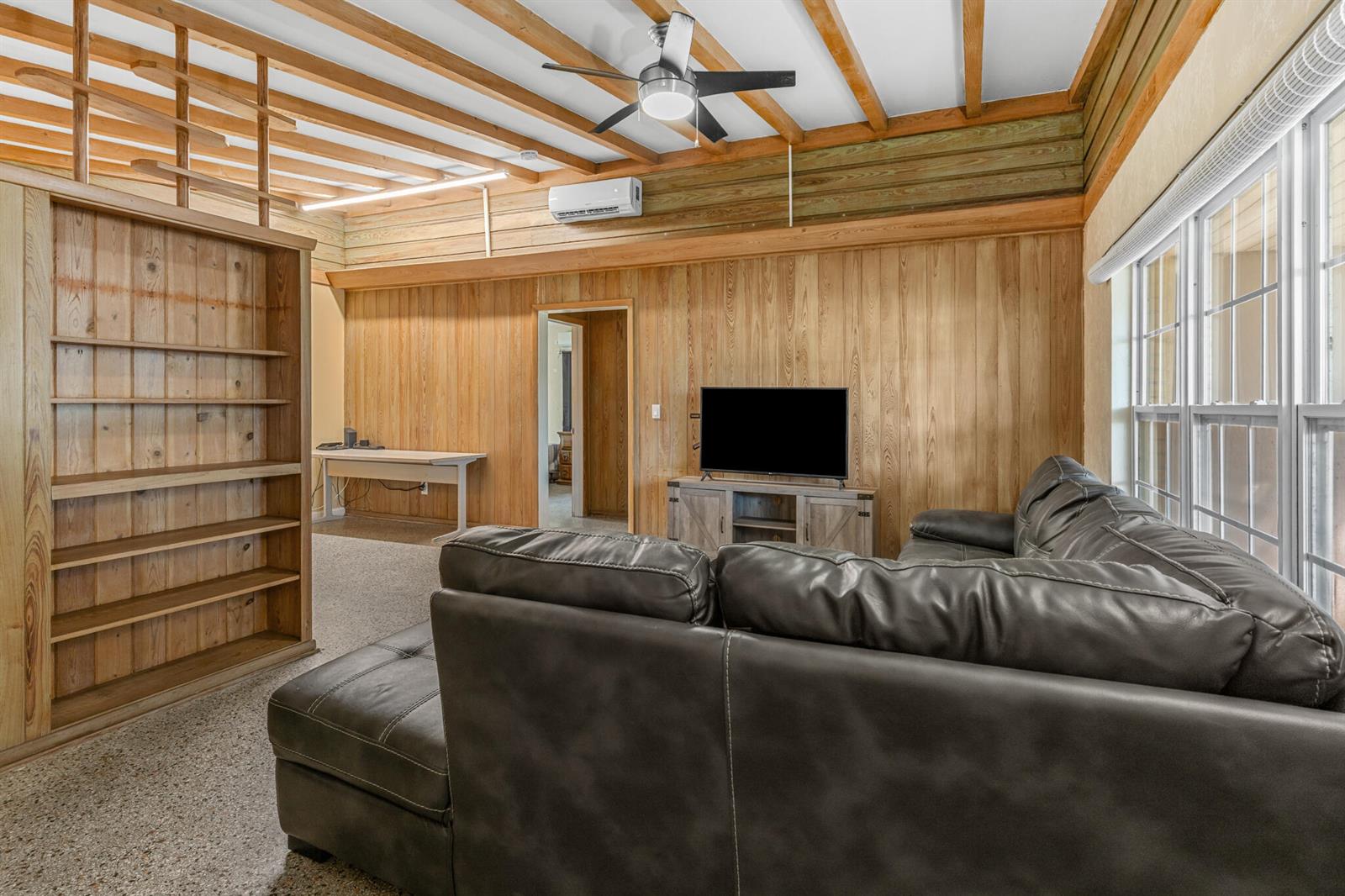 A living room features wood-paneled walls, a ceiling fan, a sectional sofa, and built-in shelving — 2456 Cortez Avenue, Vero Beach FL 32960, VERO BEACH, FL