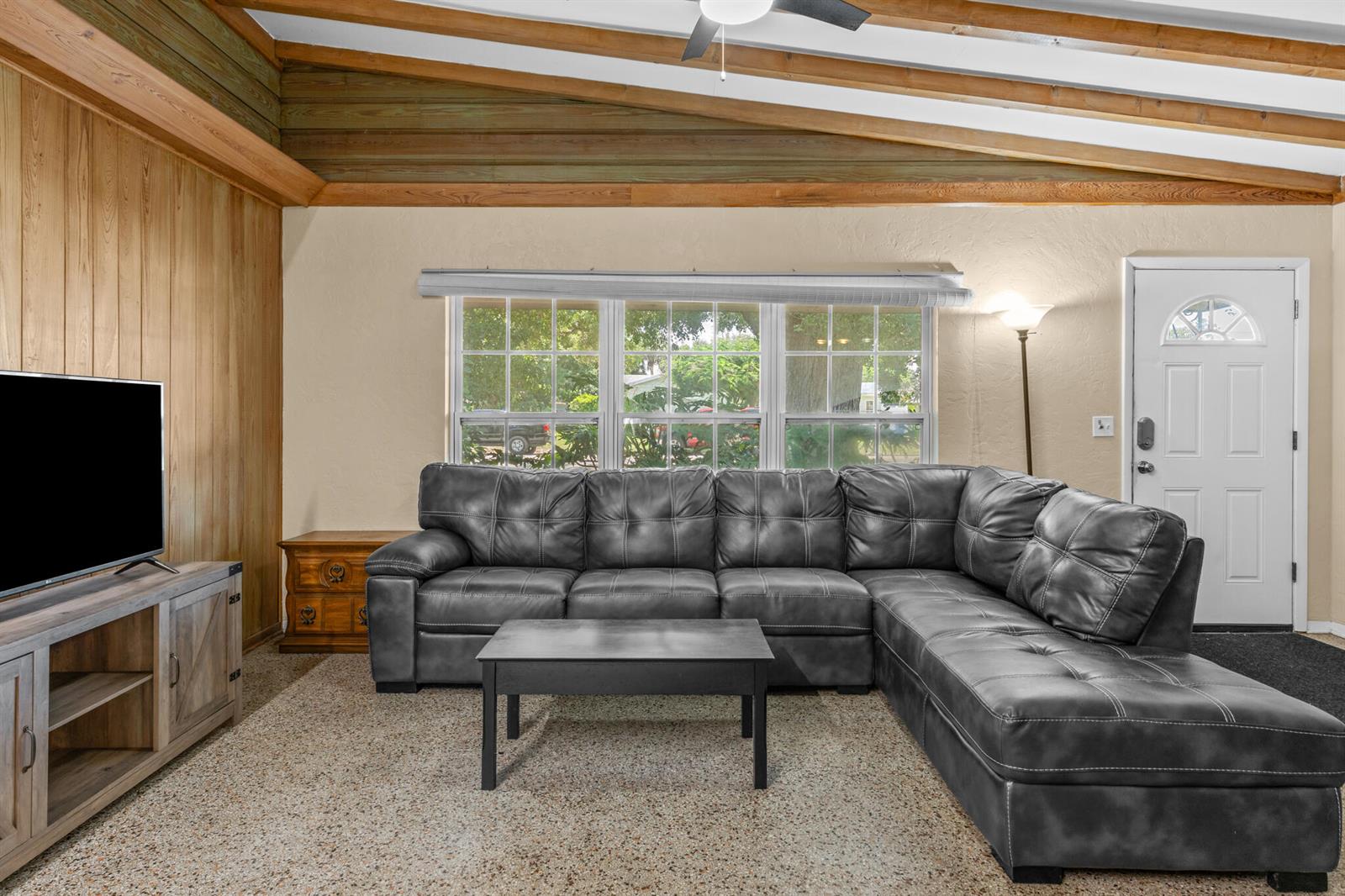 A living room features a gray sectional sofa, wood-paneled walls, and a vaulted ceiling — 2456 Cortez Avenue, Vero Beach FL 32960, VERO BEACH, FL