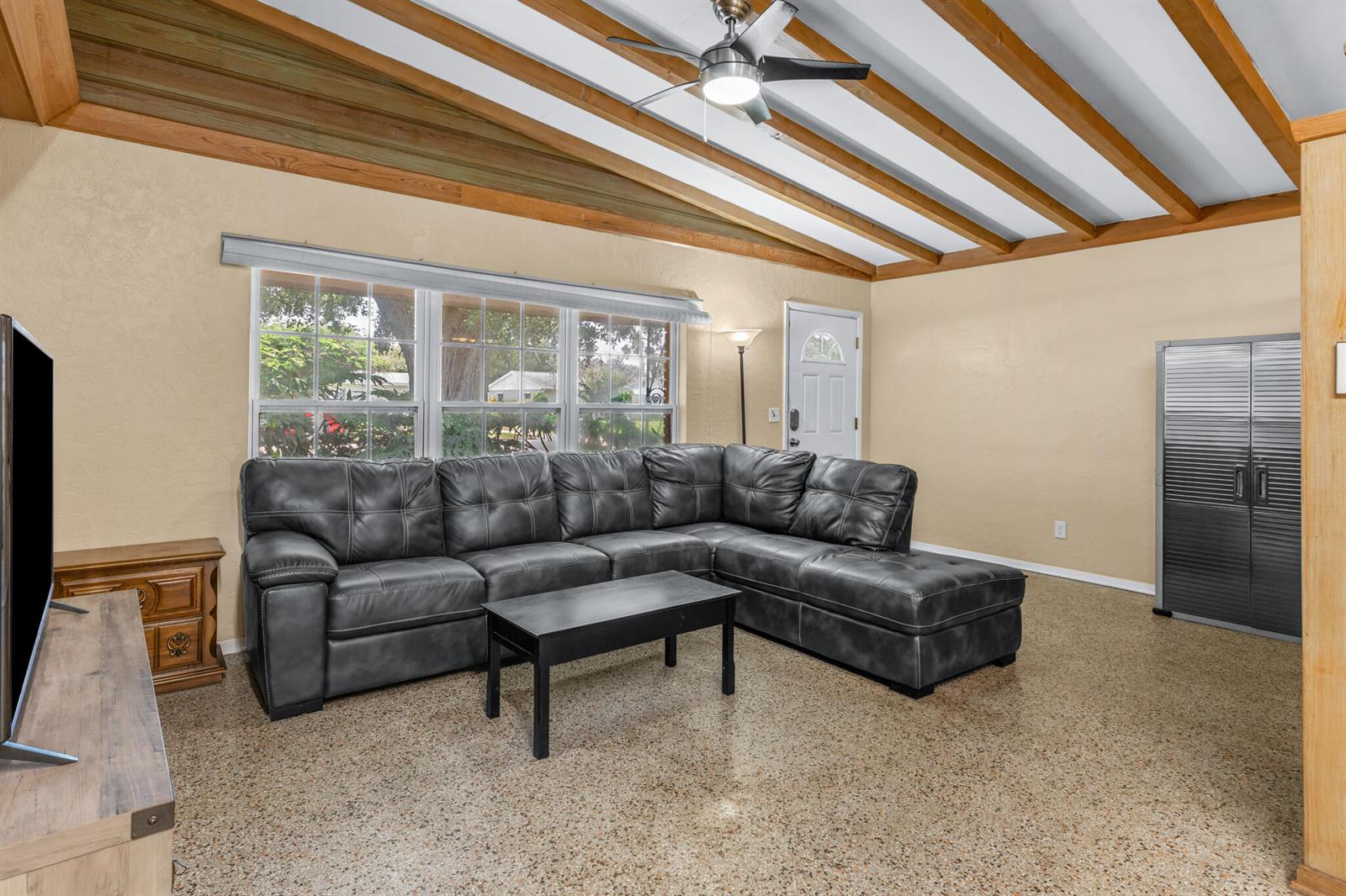 A living room features a grey sectional sofa, vaulted wood-beamed ceiling, and speckled flooring — 2456 Cortez Avenue, Vero Beach FL 32960, VERO BEACH, FL