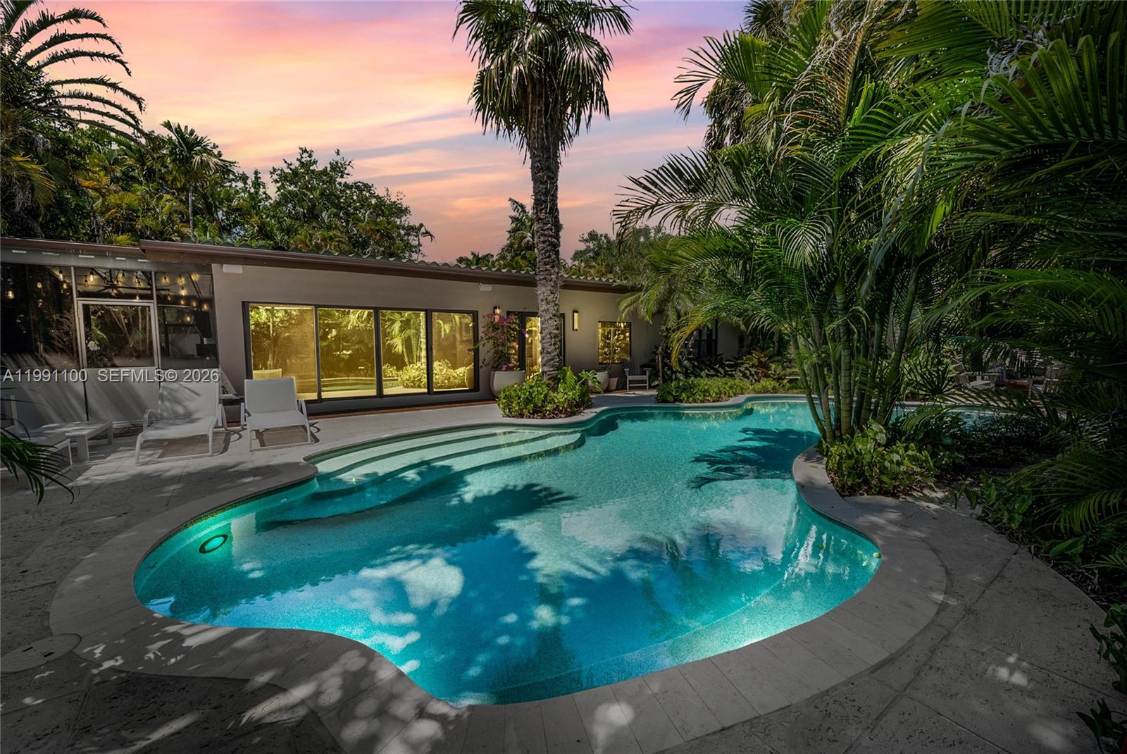 A swimming pool with steps sits on a patio next to a house with palm trees — 3620 Battersea Rd, Miami FL 33133, MIAMI, FL