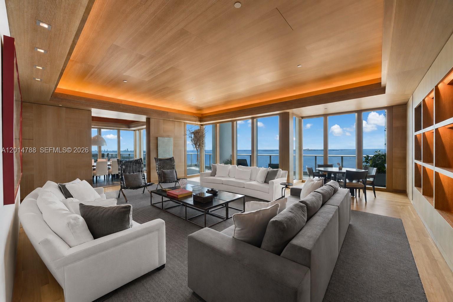 A modern living room features wood-paneled walls and ceilings, white sofas, and floor-to-ceiling ocean views — 2627 S Bayshore Dr # 3201, Miami FL 33133, MIAMI, FL