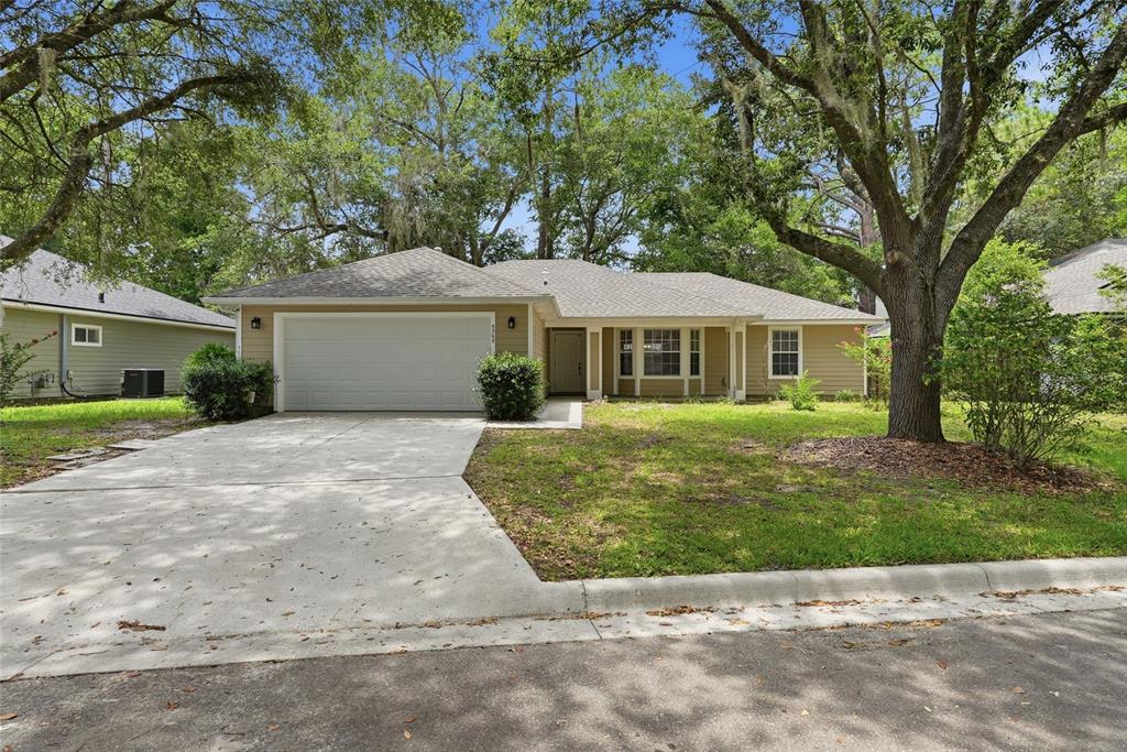 A single-story house with tan siding, a two-car garage, and a front lawn with trees — 4308 NW 35TH TERRACE, GAINESVILLE, FL
