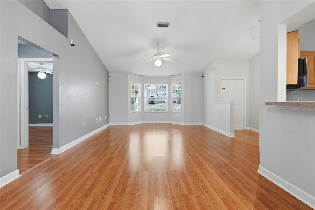 An empty living room features light gray walls, wood-look flooring, and a bay window — 4308 NW 35TH TERRACE, GAINESVILLE, FL