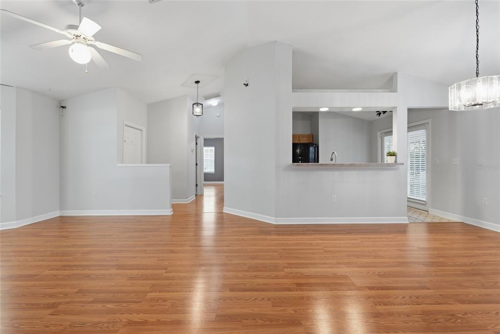 A living room with light gray walls, wood-look flooring, a ceiling fan, and a kitchen pass-through — 4308 NW 35TH TERRACE, GAINESVILLE, FL