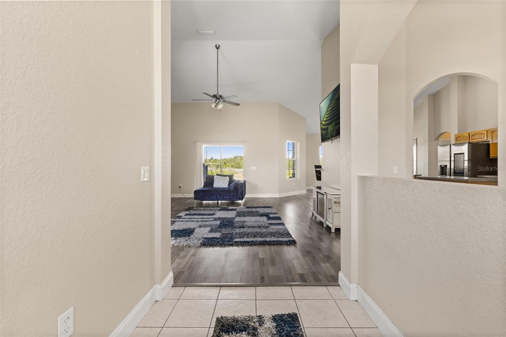 A tiled entryway leads into a living room with wood-look flooring and a vaulted ceiling — 10377 SW 38TH AVENUE, OCALA, FL