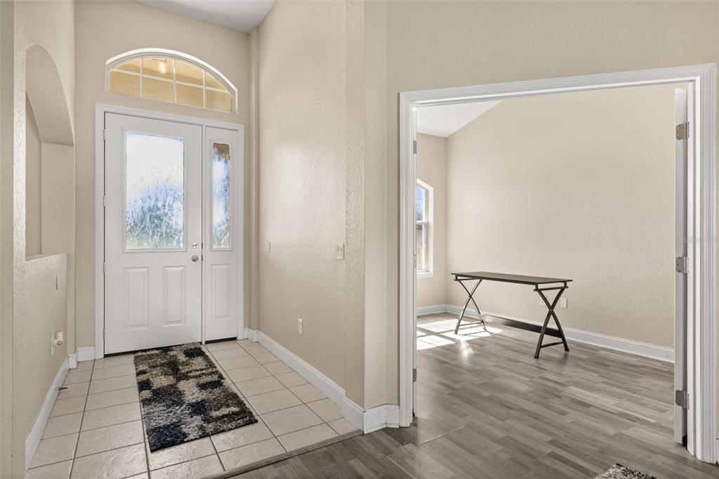 An entryway with tile flooring leads to a room with wood-look floors and a desk — 10377 SW 38TH AVENUE, OCALA, FL