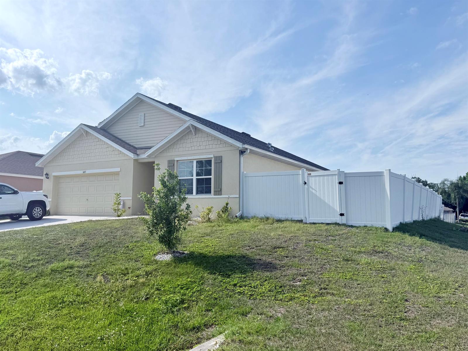 A single-story house with a beige exterior, a two-car garage, and a white vinyl fence — 1405 Pace Drive NW, Palm Bay FL 32907, PALM BAY, FL