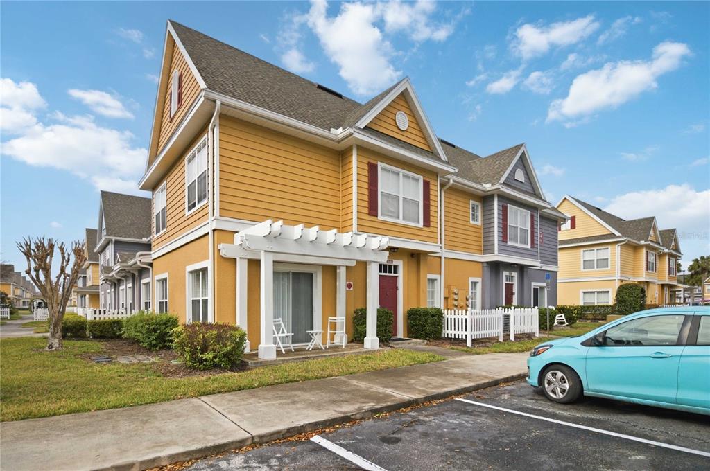 A yellow two-story townhouse with a white pergola and a small front patio — 2620 LODI CIRCLE UNIT 101, KISSIMMEE, FL