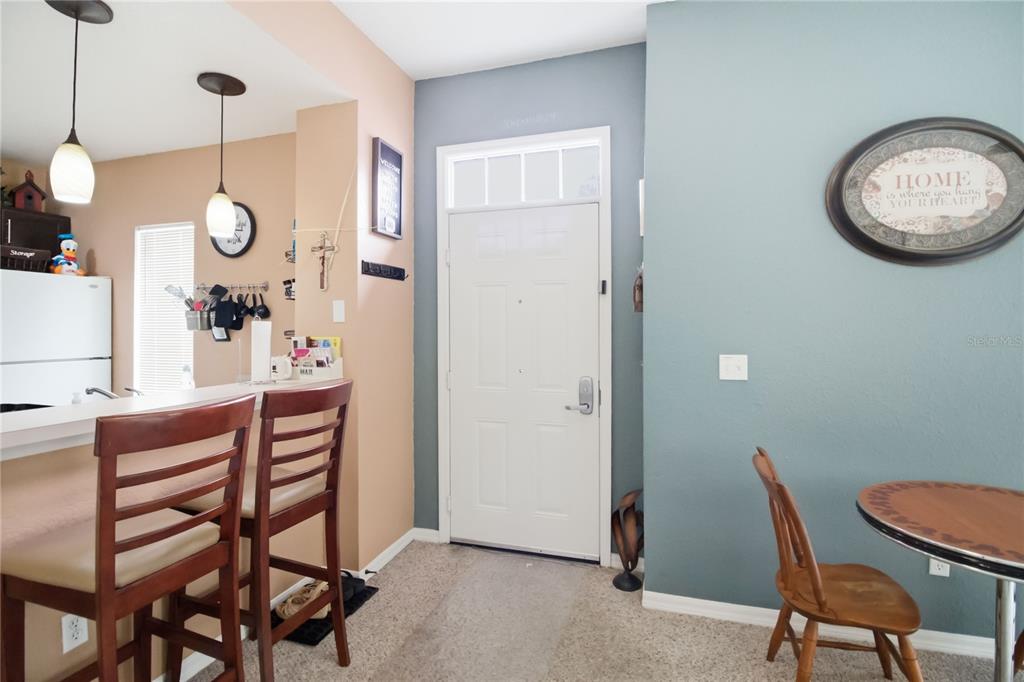 An entryway features a white front door, a breakfast bar with stools, and blue walls — 2620 LODI CIRCLE UNIT 101, KISSIMMEE, FL