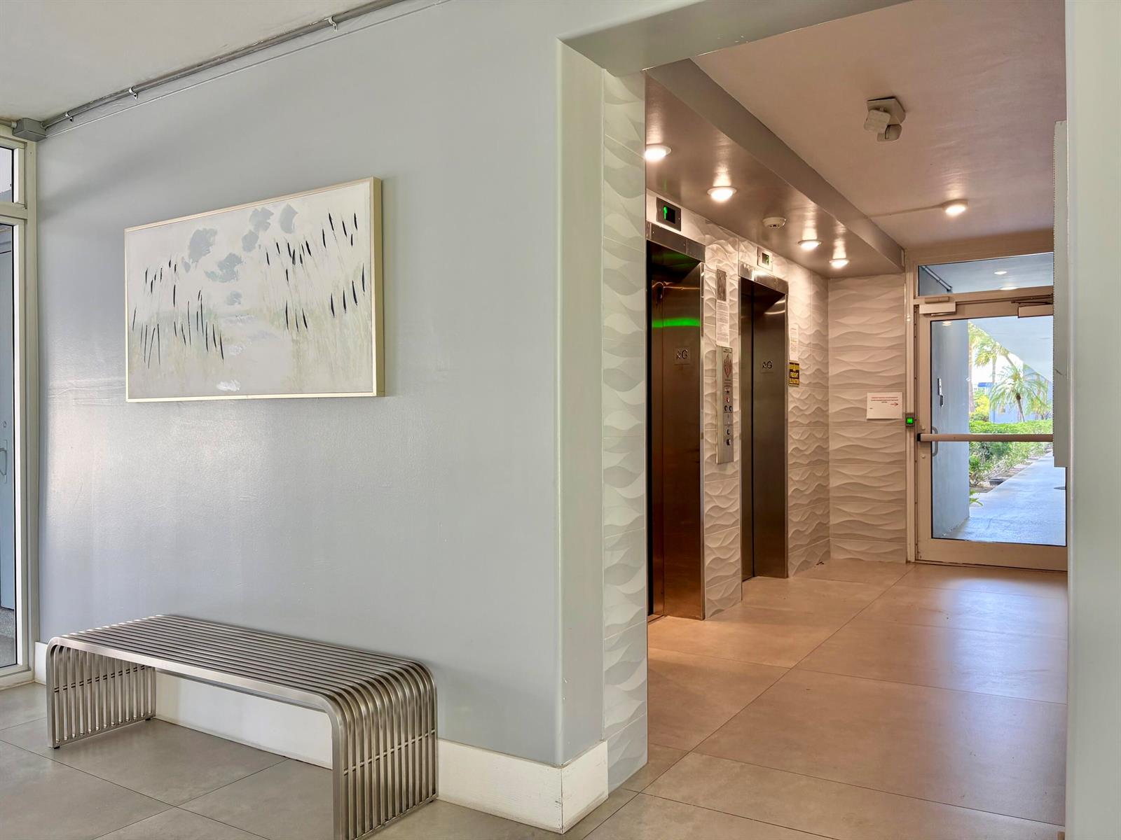 A modern lobby features a metal bench, a framed painting, and two elevators — 5700 NW 2nd Avenue # 203, Boca Raton FL 33487, BOCA RATON, FL