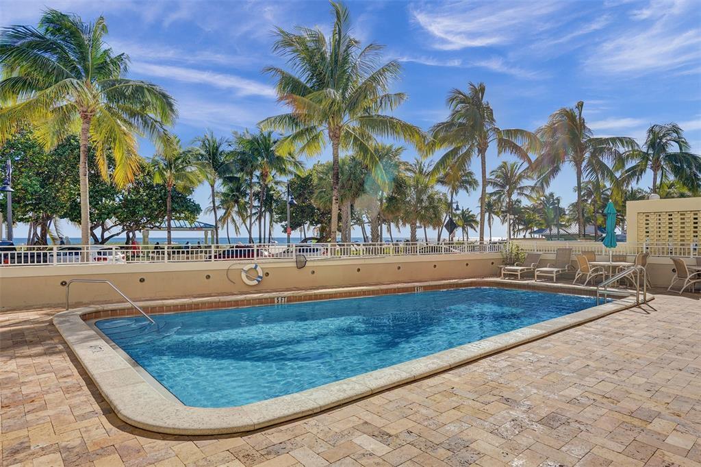 A rectangular swimming pool sits on a stone patio surrounded by palm trees and fencing — 133 N Pompano Beach Blvd Boulevard # 7, Pompano Beach FL 33062, POMPANO BEACH, FL