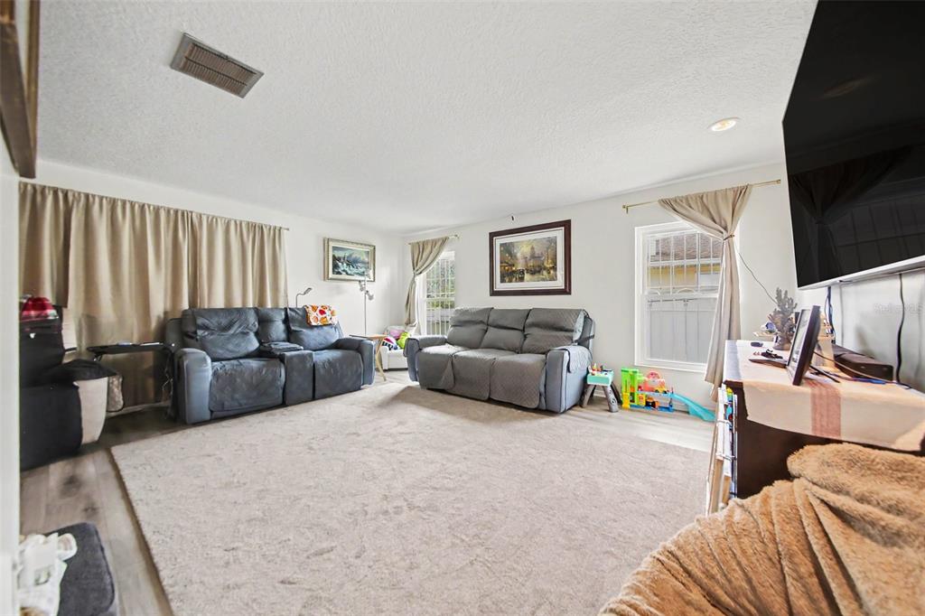 A living room features two gray sofas, a large area rug, and two windows — 394 BARBERRY LANE, ALTAMONTE SPRINGS, FL