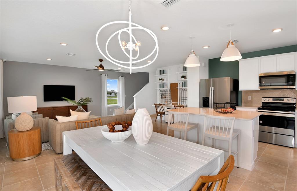An open-concept living and dining area features a white table, kitchen island, and gray walls — 10430 HIDDEN BANKS GLEN, PARRISH, FL