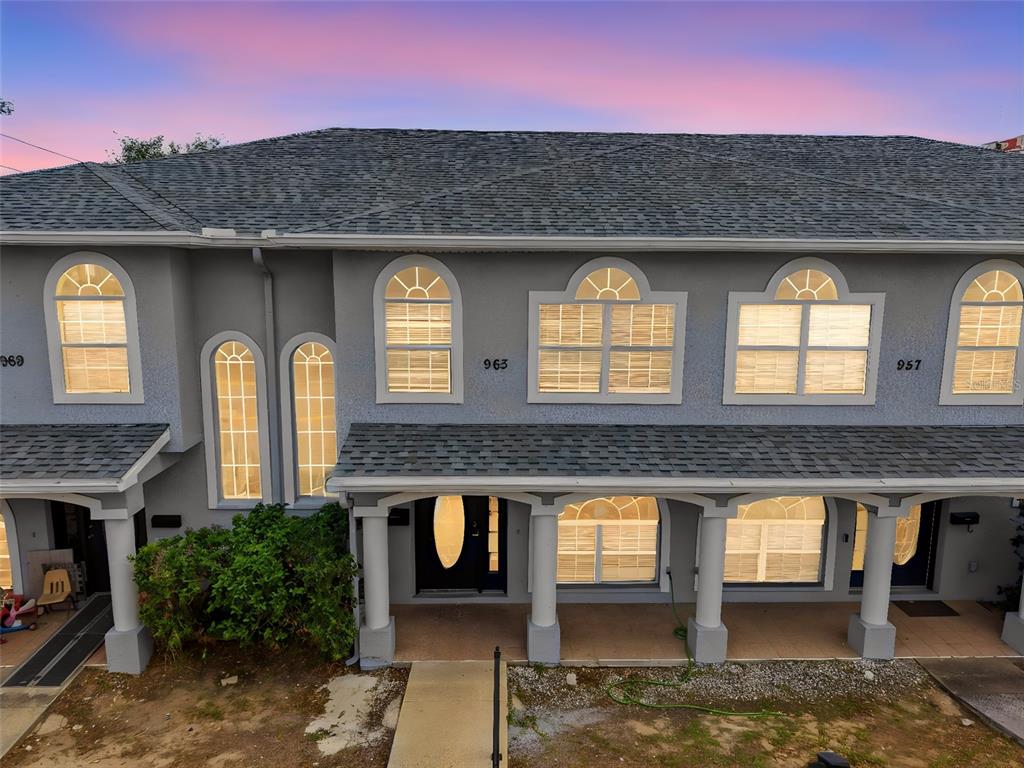 A gray multi-unit townhouse exterior features arched windows, a covered porch, and a shingled roof — 963 E MAIN STREET, HAINES CITY, FL