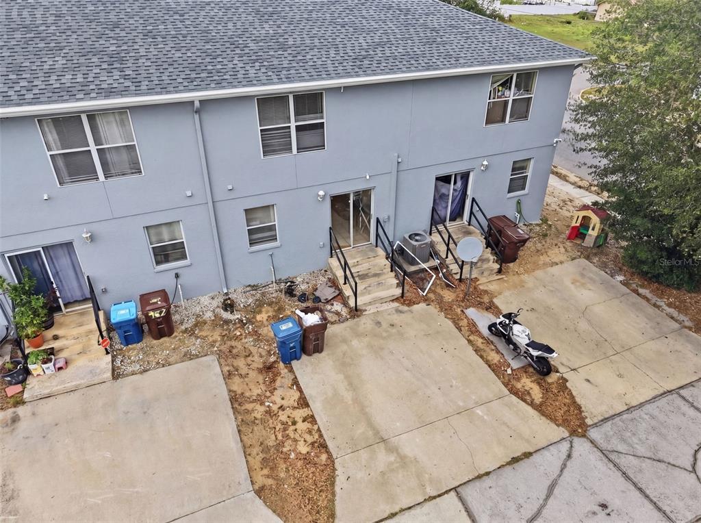 An aerial view shows the rear exterior of a two-story townhouse with concrete parking pads — 963 E MAIN STREET, HAINES CITY, FL