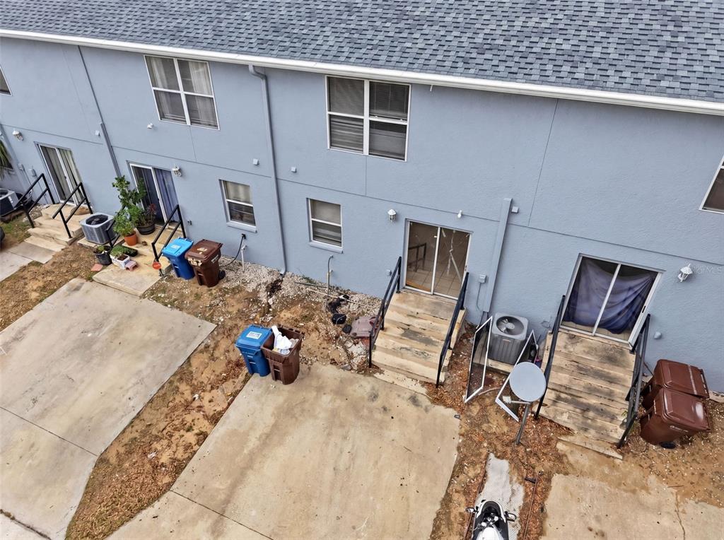 An aerial view shows the back of a multi-unit building with concrete patios and stairs — 963 E MAIN STREET, HAINES CITY, FL