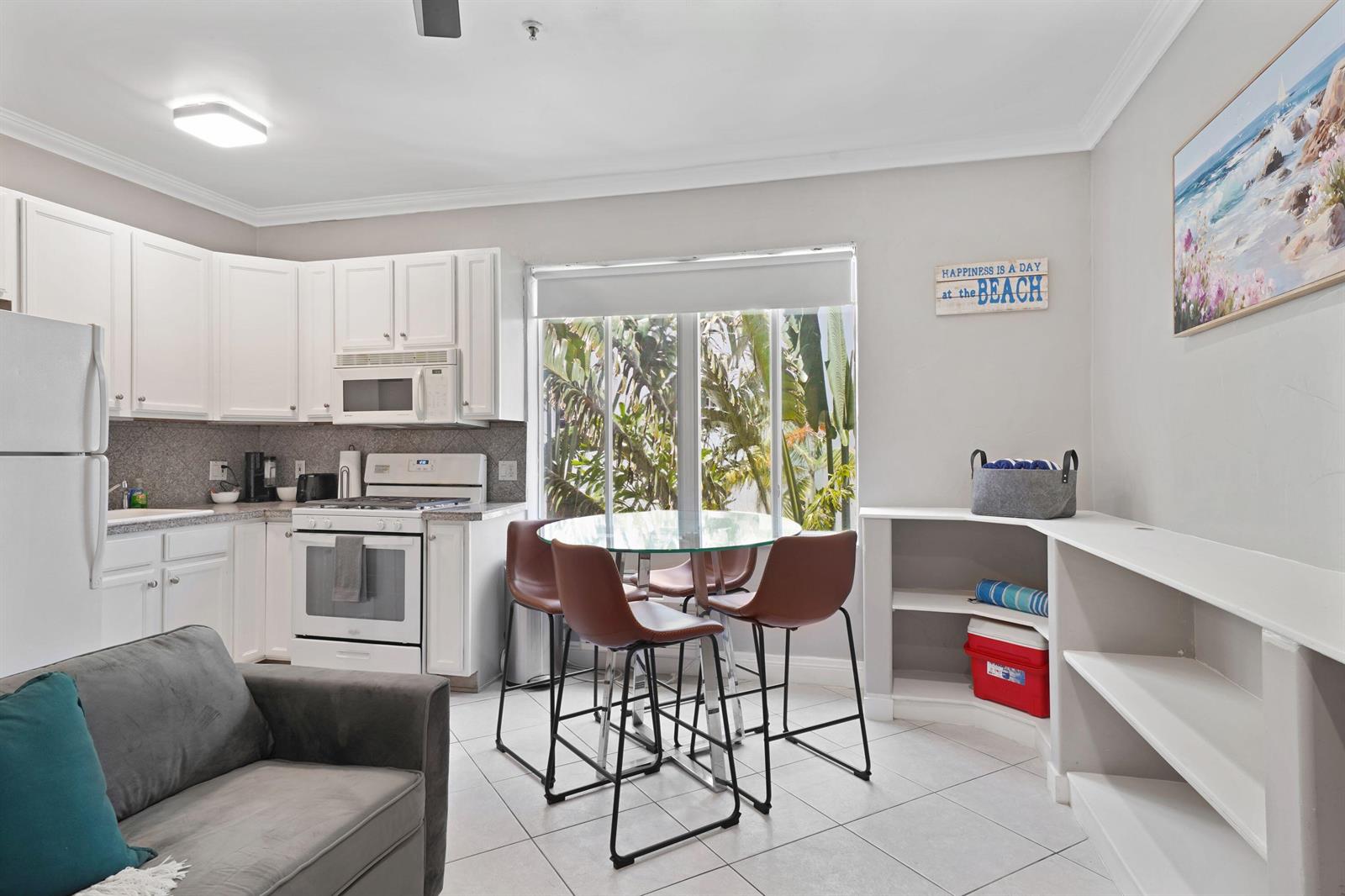 A kitchen and dining area features white cabinetry, a glass table, and a grey sofa — 3710 Collins Avenue # 304, Miami Beach FL 33140, MIAMI BEACH, FL