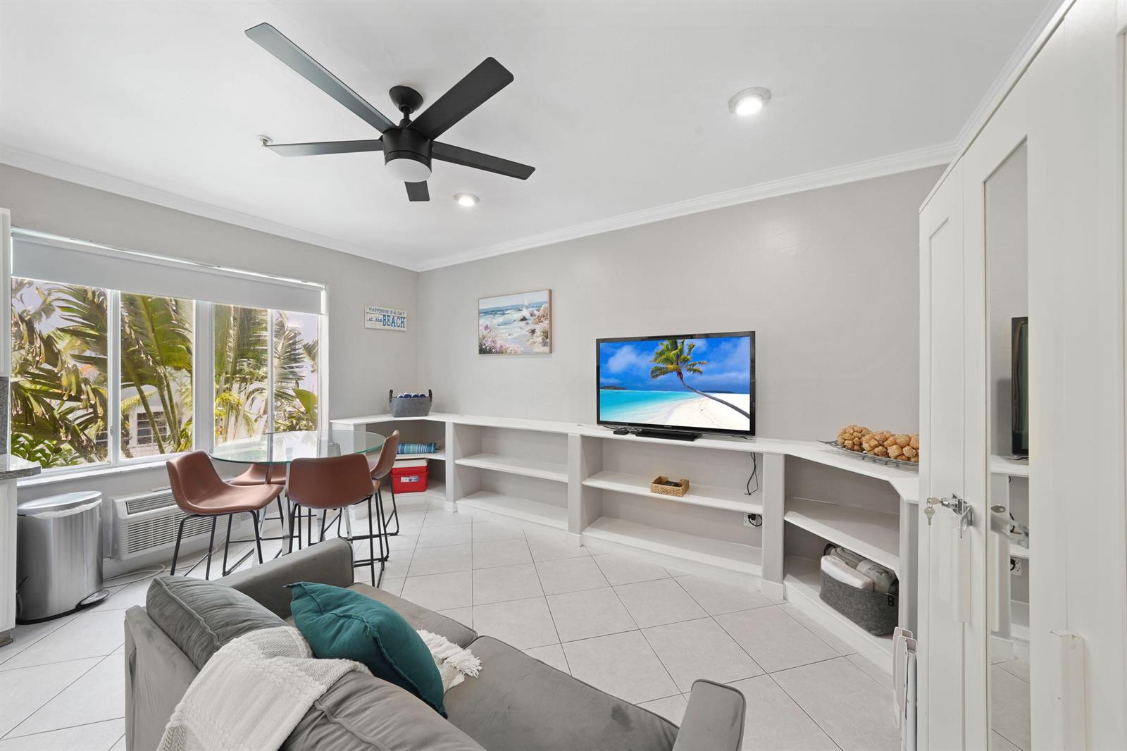 A living room features a ceiling fan, tiled floors, built-in shelving, and a dining area — 3710 Collins Avenue # 304, Miami Beach FL 33140, MIAMI BEACH, FL