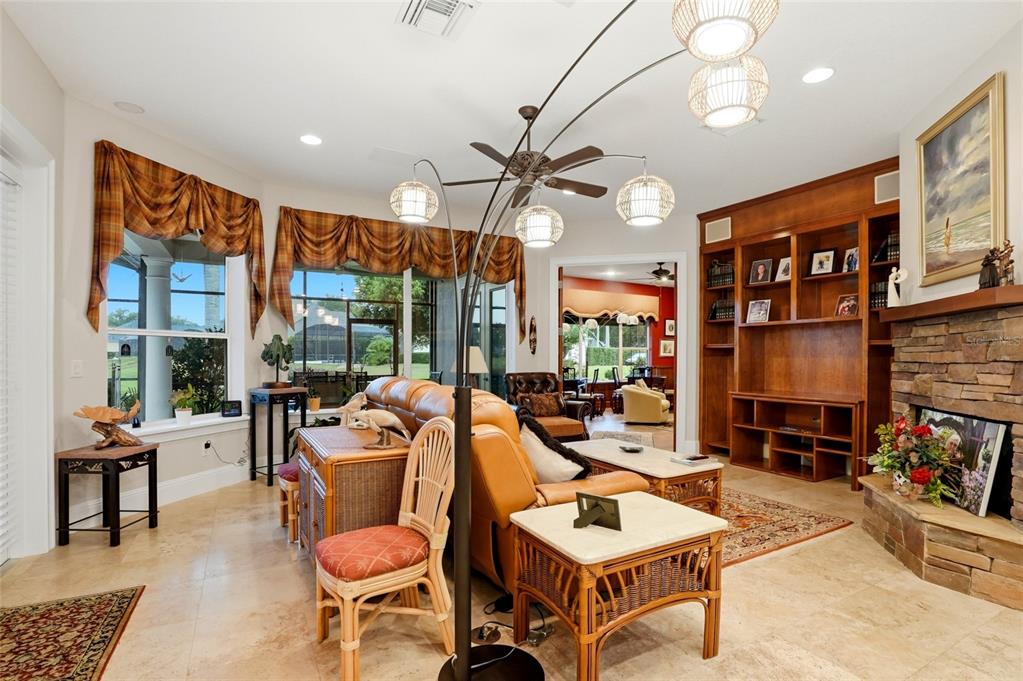 A living room features a stone fireplace, built-in wooden shelving, and a large arched floor lamp — 1059 CEASARS COURT, MOUNT DORA, FL