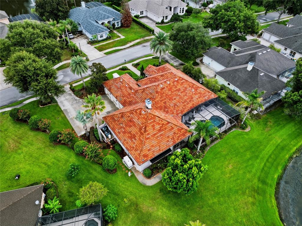 An aerial view of a house with a red tile roof and a screened pool — 1059 CEASARS COURT, MOUNT DORA, FL