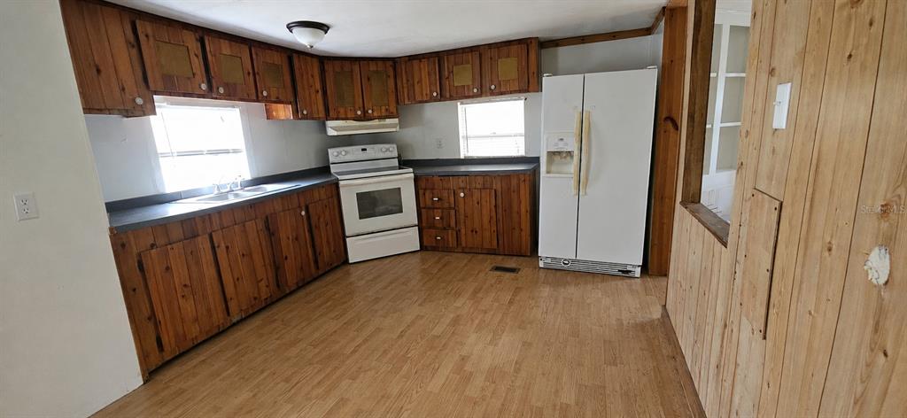 A kitchen features wood cabinets, a white stove, a white refrigerator, and wood-look flooring — 702 DAVID AVENUE, INTERLACHEN, FL