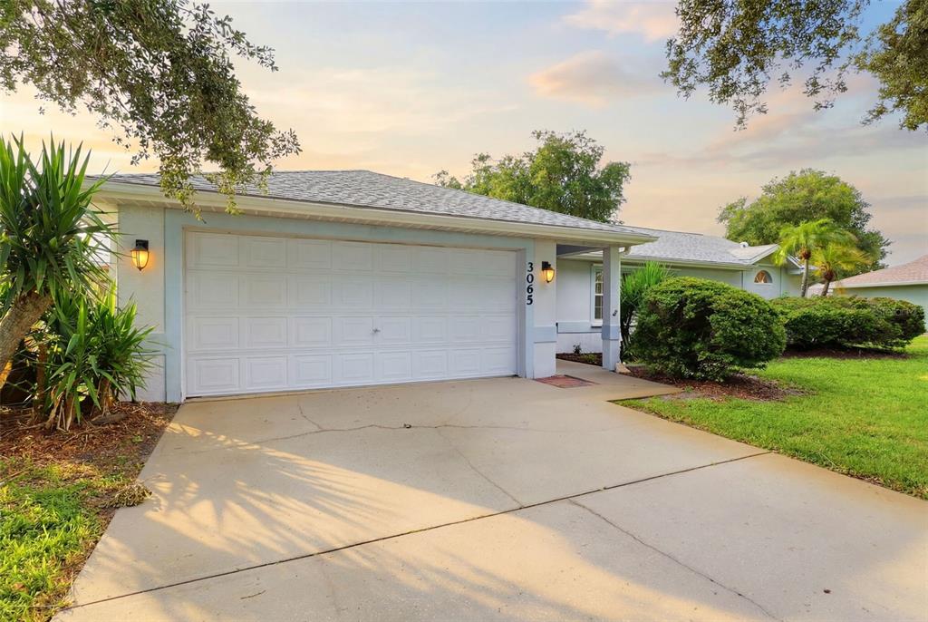 A single-story house with a white garage door, concrete driveway, and landscaped front yard — 3065 PINEDA CROSSING DRIVE, MELBOURNE, FL