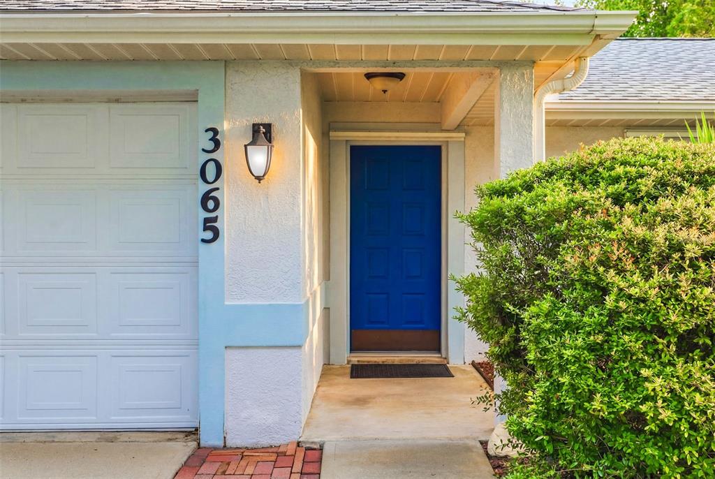 A blue front door is set in a white exterior wall next to a garage — 3065 PINEDA CROSSING DRIVE, MELBOURNE, FL