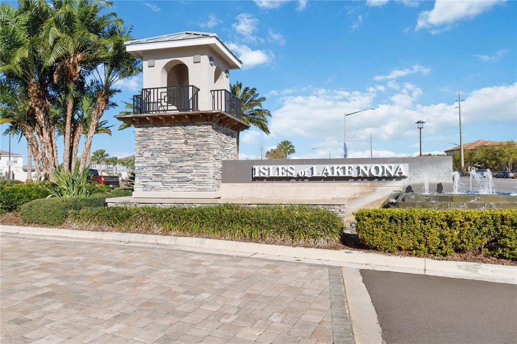 A stone monument sign for Isles of Lake Nona stands beside a fountain and palm trees — 14366 LANIKAI BEACH DRIVE, ORLANDO, FL