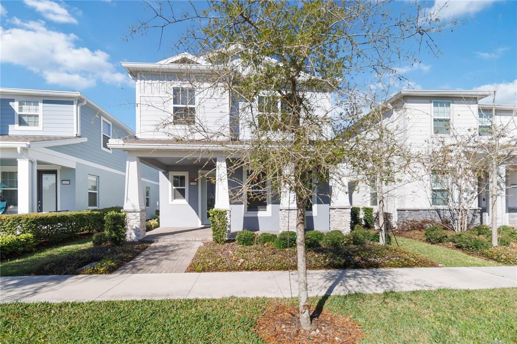 A two-story house with a front porch, light-colored siding, and a paved walkway — 14366 LANIKAI BEACH DRIVE, ORLANDO, FL