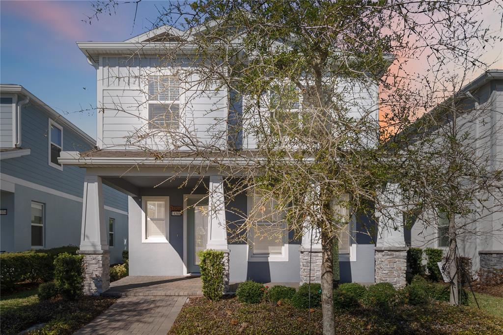 A two-story house with light blue siding, a covered front porch, and stone-based columns — 14366 LANIKAI BEACH DRIVE, ORLANDO, FL