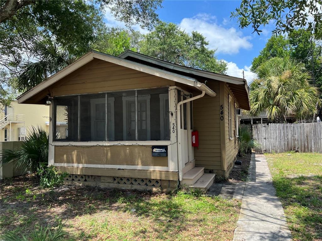 A small, brown, single-story house features a screened-in front porch and a concrete walkway — 540 14TH STREET N, ST PETERSBURG, FL