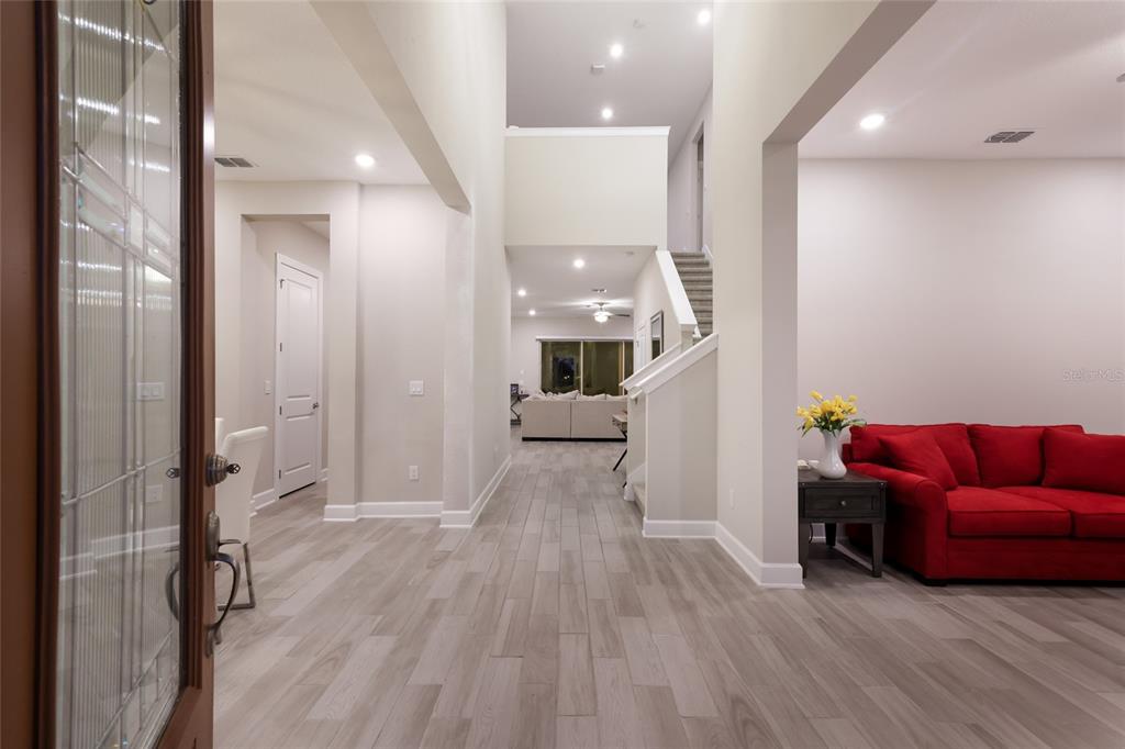 An entryway leads into a living area with light wood-look flooring and a red sofa — 3533 BIG SKY WAY, LAKEWOOD RANCH, FL