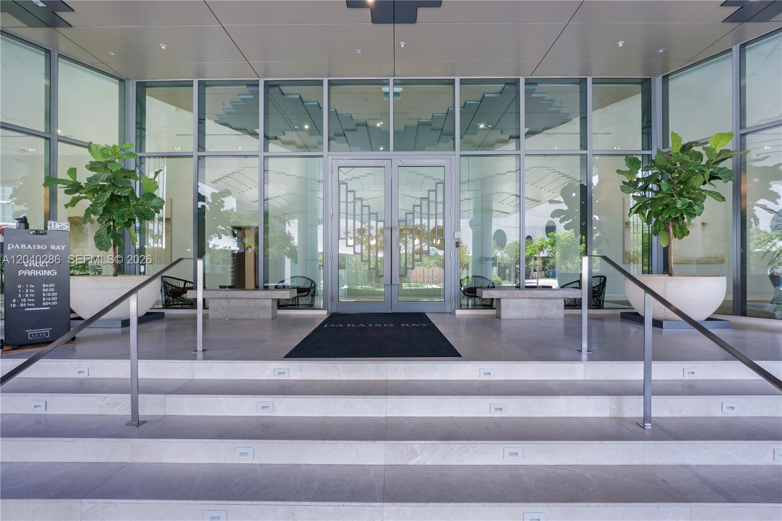 The entrance to a building features glass doors, stone steps, and two large potted plants — 650 NE 32nd St # 703, Miami FL 33137, MIAMI, FL