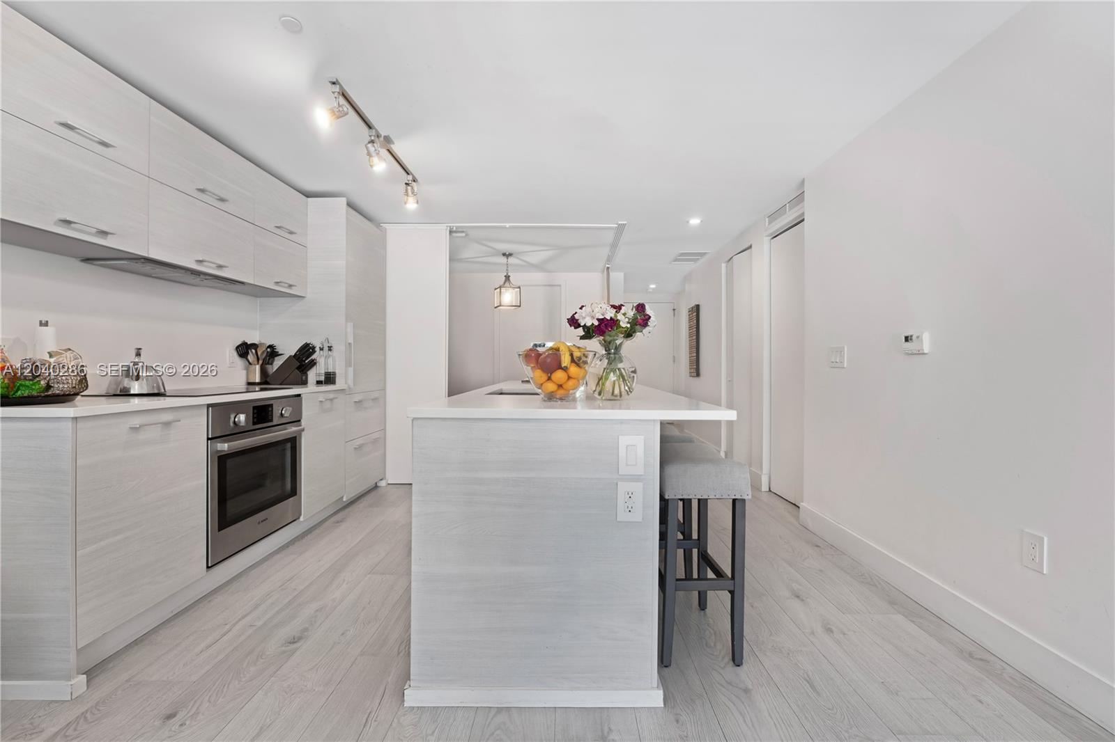 A modern kitchen features light wood cabinetry, stainless steel appliances, and a central island — 650 NE 32nd St # 703, Miami FL 33137, MIAMI, FL